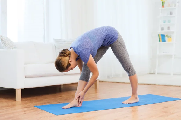 Женщина делает yoga интенсивная поза растяжения на циновке — стоковое фото