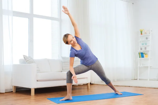 Mujer haciendo yoga bikram triángulo pose en la estera — Foto de Stock