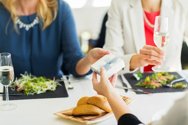 Primer plano de las mujeres dando regalo en el restaurante — Foto de Stock