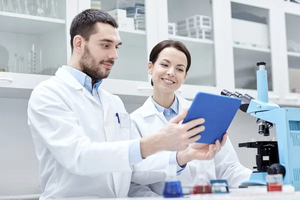 Cientistas com tablet pc e microscópio em laboratório — Fotografia de Stock