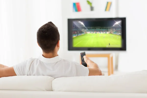 Man watching football game on tv at home from back — ストック写真