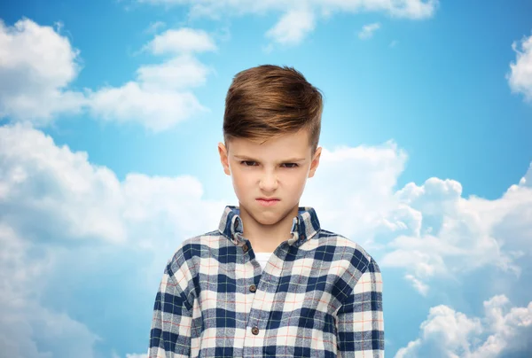 Сердитий хлопчик у картатій сорочці над блакитним небом — стокове фото