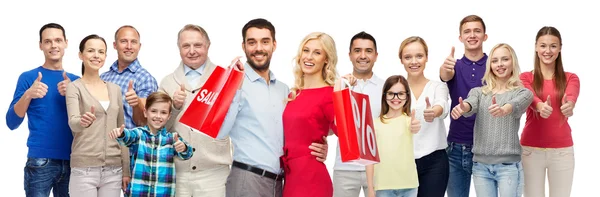 Gente feliz con bolsas de compras mostrando los pulgares hacia arriba — Foto de Stock