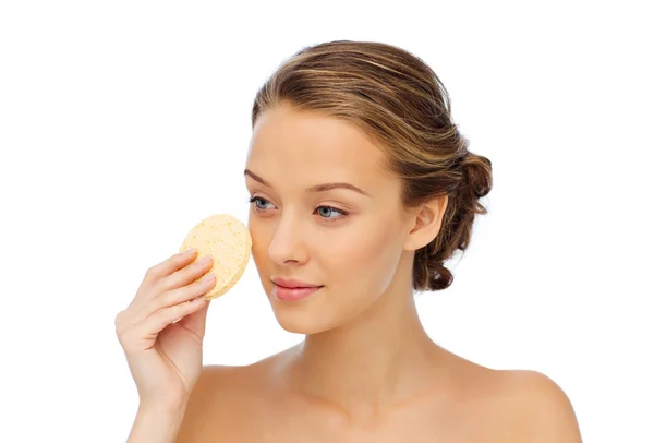 Young woman cleaning face with exfoliating sponge — Stock Photo, Image