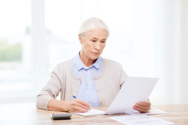 Senior woman with papers and calculator at home — Stock Photo, Image