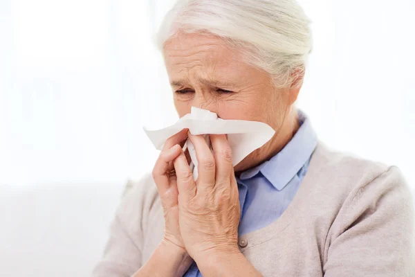 Zieke senior vrouw blazen neus aan papier servet — Stockfoto