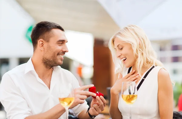 Gelukkige paar met verlovingsring en wijn in café — Stockfoto