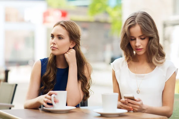 Kobiety z smartfonów i napić się kawy w kawiarni na świeżym powietrzu — Zdjęcie stockowe