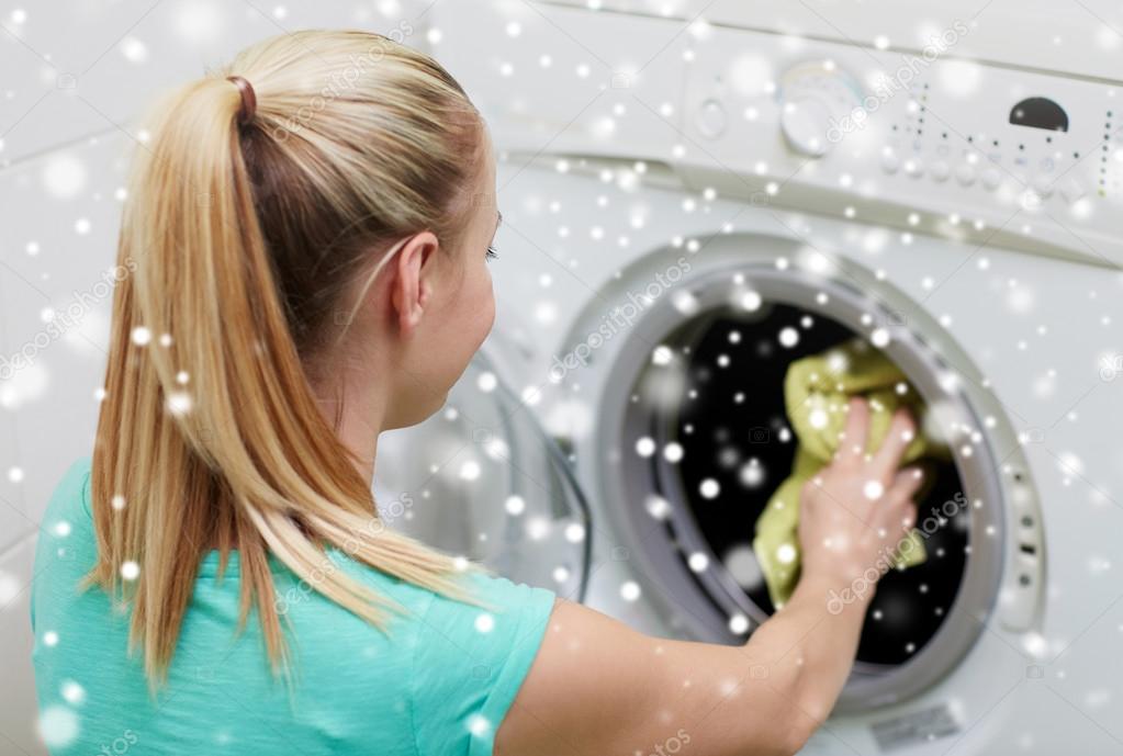 Mulher feliz colocando roupa na máquina de lavar em casa fotos, imagens de © Syda_Productions