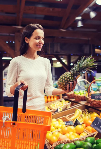 Gelukkig jonge vrouw met levensmiddelen mand in markt — Stockfoto