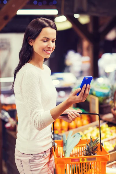 Donna felice con cesto e smartphone nel mercato — Foto Stock