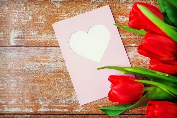 Close up of tulips and greeting card with heart — Stock Photo, Image