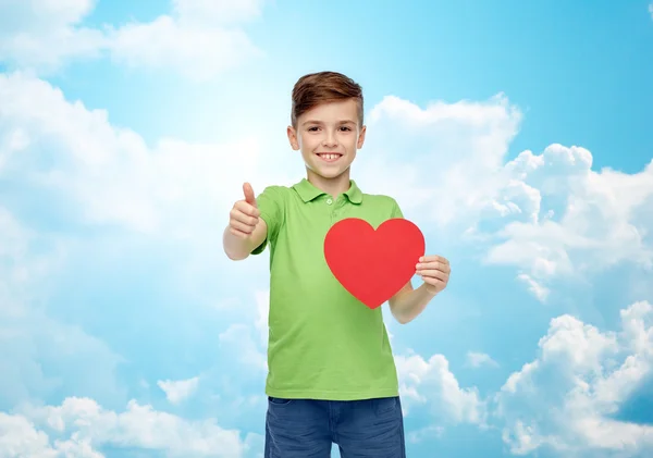 Niño feliz mostrando forma de corazón rojo y pulgares hacia arriba — Foto de Stock