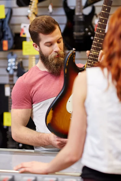 Asistente mostrando la guitarra del cliente en la tienda de música — Foto de Stock