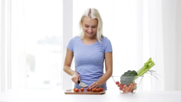 Smiling young woman chopping tomatoes at home — Stock Video