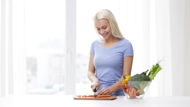 Sonriente joven mujer picando verduras en casa — Vídeos de Stock