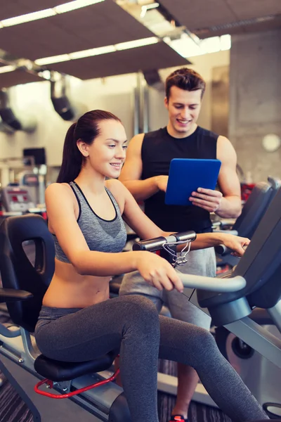 Happy woman with trainer on exercise bike in gym — Stock Photo, Image