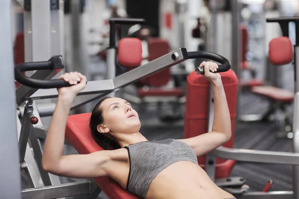 Mujer joven haciendo ejercicio en la máquina de gimnasio — Foto de Stock