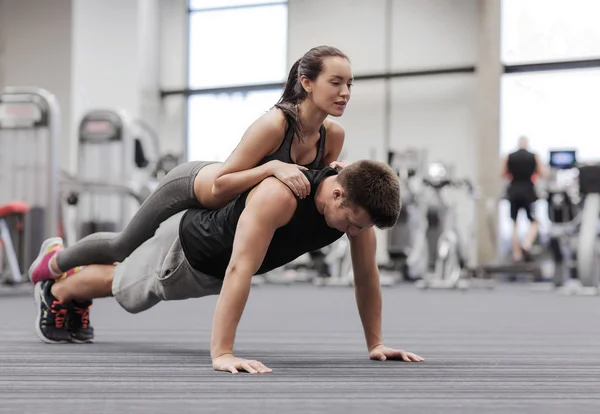 Coppia sorridente facendo flessioni in palestra — Foto Stock