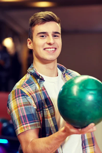 Gelukkig jonge man houden bal in bowlingclub — Stockfoto