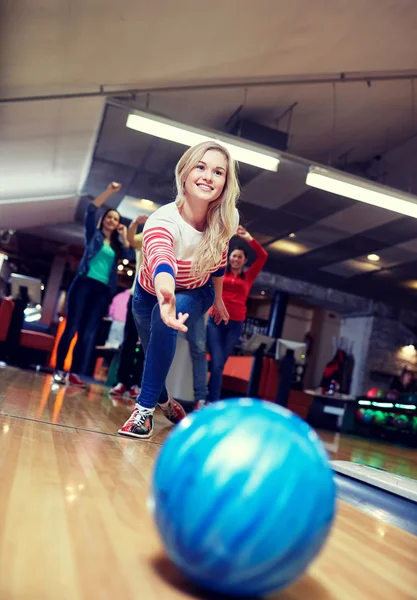 Happy young woman throwing ball in bowling club — Stock Photo, Image