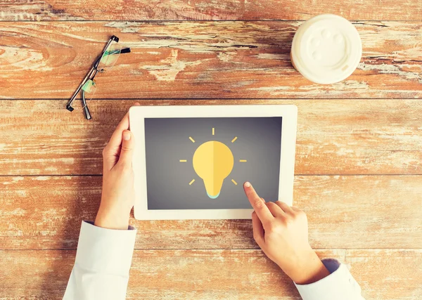 Close up of hands with lighting bulb on tablet pc — Stock Photo, Image