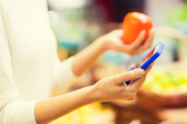 Kvinna med smartphone och persimon på marknaden — Stockfoto