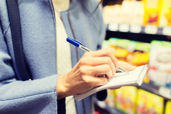 Nahaufnahme einer Frau, die auf dem Markt an Notizblock schreibt — Stockfoto