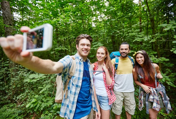Amigos con mochila tomando selfie por teléfono inteligente —  Fotos de Stock