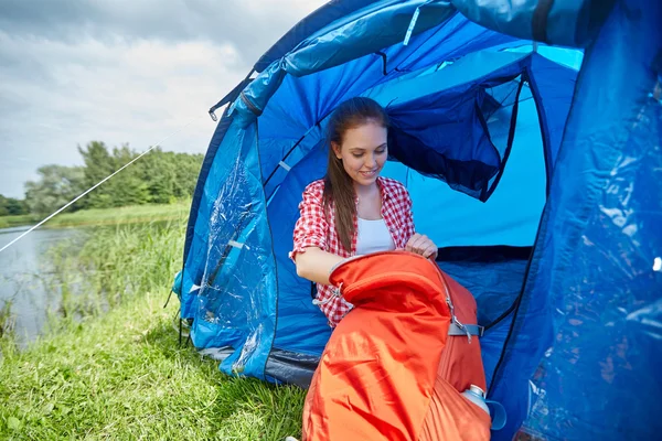 Feliz jovem mulher sentada na tenda no acampamento — Fotografia de Stock