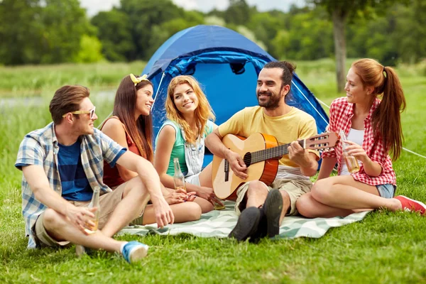 Amigos felizes com bebidas e guitarra no acampamento — Fotografia de Stock