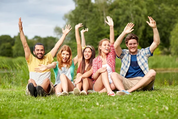 Grupp leende vänner viftande händer utomhus — Stockfoto