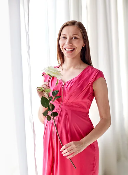 Mujer embarazada feliz con flor de rosa en casa — Foto de Stock