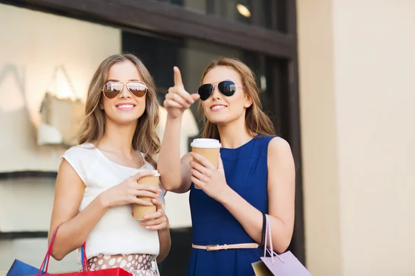 Mulheres jovens com sacos de compras e café na loja — Fotografia de Stock