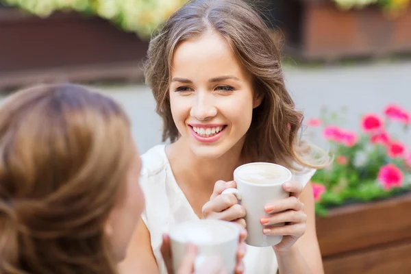 Улыбающиеся молодые женщины с чашками кофе в кафе — стоковое фото
