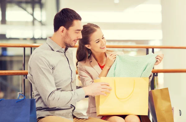 Feliz jovem casal com sacos de compras no shopping — Fotografia de Stock