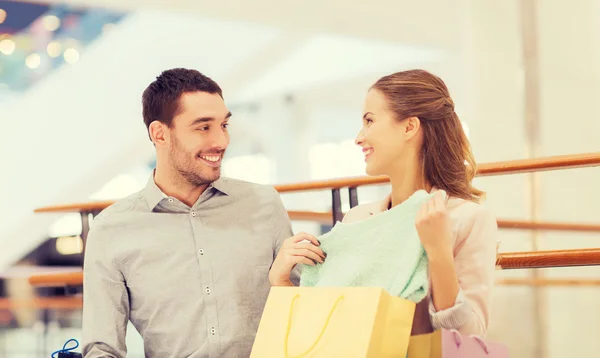 Feliz jovem casal com sacos de compras no shopping — Fotografia de Stock