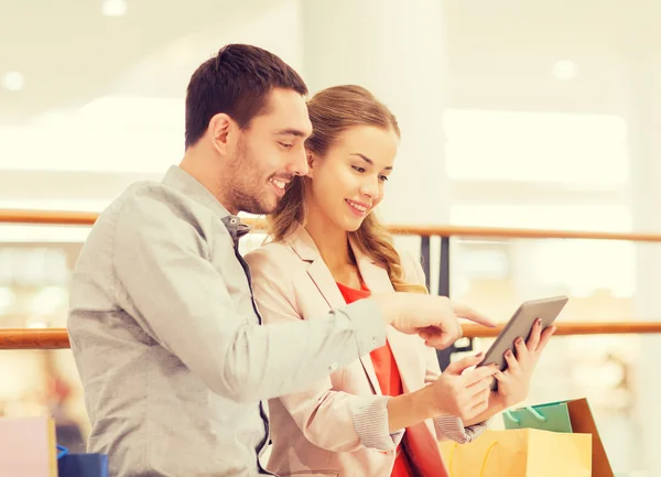 Couple with tablet pc and shopping bags in mall — Stock Photo, Image