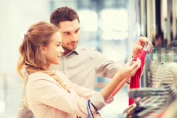 Happy young couple choosing dress in mall — Stock Photo, Image