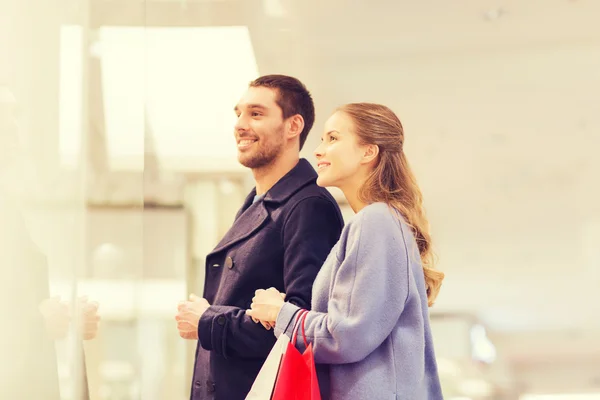 Feliz jovem casal com sacos de compras no shopping — Fotografia de Stock