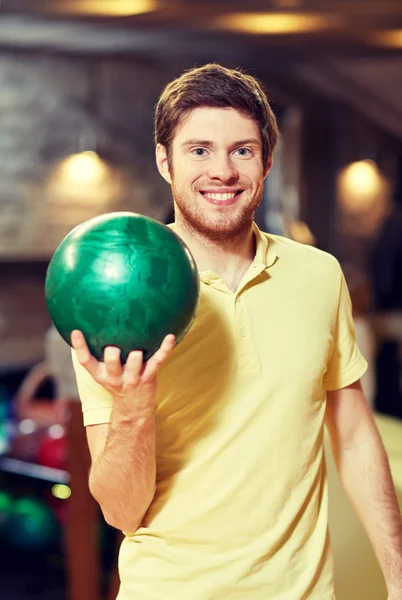 Happy young man holding ball in bowling club — Stock Photo, Image