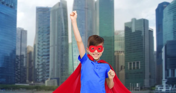 Piros szuperhős cape és a maszkot mutatja ököllel a fiú — Stock Fotó
