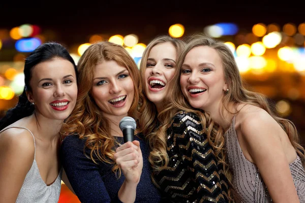 Happy women with microphone singing over lights — Stok fotoğraf