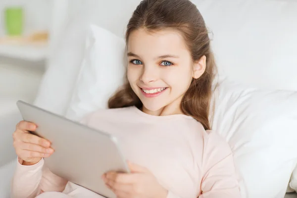 Chica feliz acostada en la cama con la tableta PC en casa — Foto de Stock