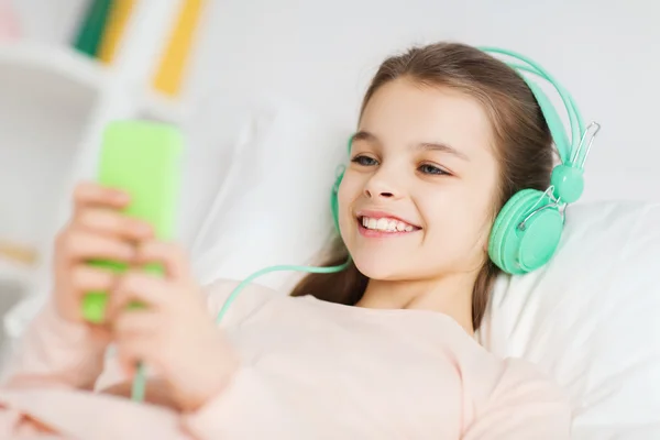 Happy girl lying in bed with smartphone at home — Stock Photo, Image