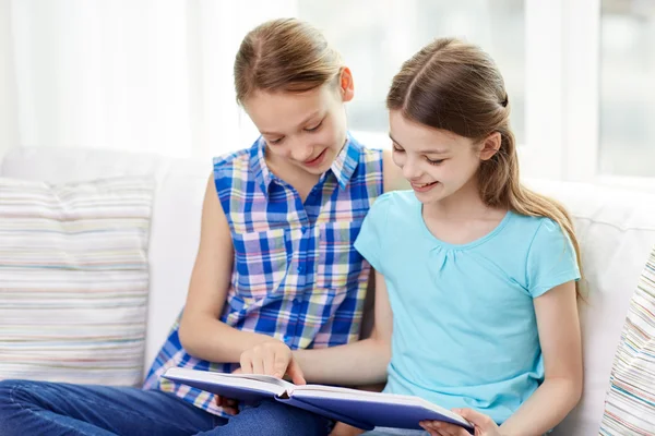 Duas meninas felizes lendo livro em casa — Fotografia de Stock