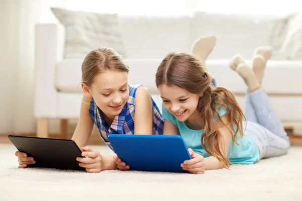Счастливые девочки с планшетным компьютером, лежащим на полу дома — стоковое фото