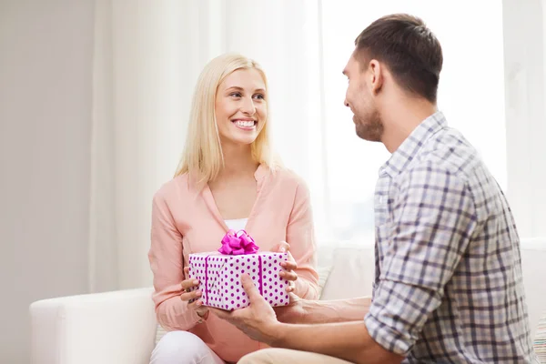 Homem feliz dando mulher caixa de presente em casa — Fotografia de Stock