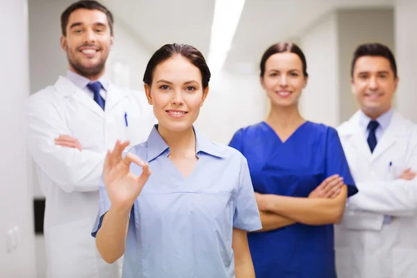 Gruppo di medici in ospedale mostrando segno mano ok — Foto Stock