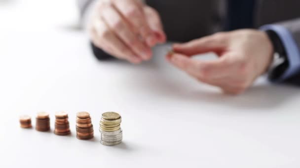 Close up of businessman putting coins into columns — Stock Video